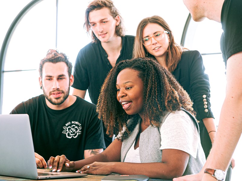Group of people engaged around a laptop smiling