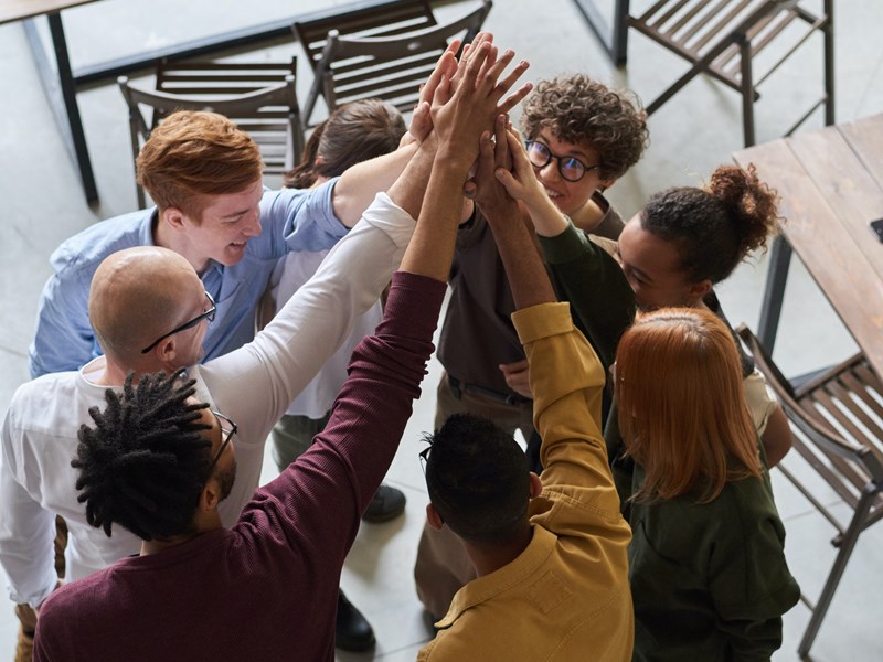 Group of young people raising their hands in a circle, embracing togetherness