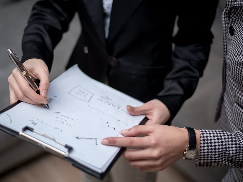 A person showing another person a clipboard with a graph on it.