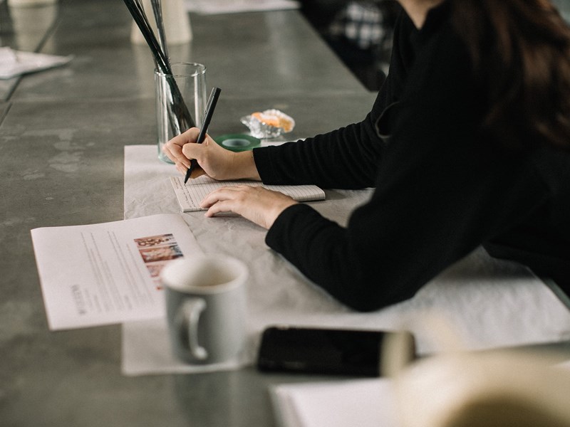 Person sat at a desk writing on paper.