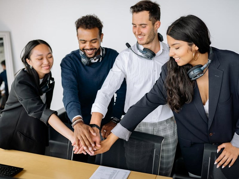 A team of people putting their hands together in a huddle.