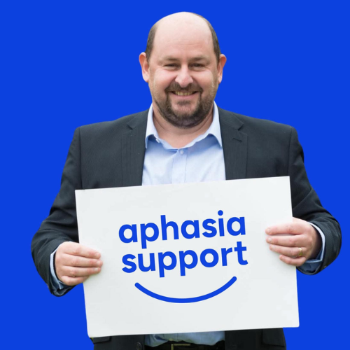 Steve Smith holding Aphasia Support logo